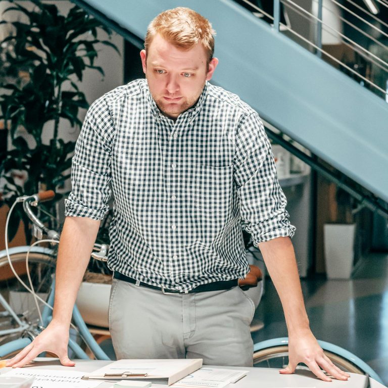 A businessman in a modern office analyzing reports on a table, showcasing teamwork and innovation.